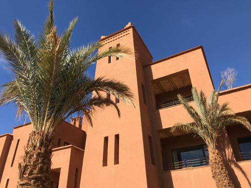 un bâtiment avec des palmiers en face de celui-ci dans l'établissement Kasbah Tamsna, à Ouarzazate