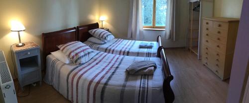two beds in a small bedroom with two lamps at The Magnolias B&B in Moyon