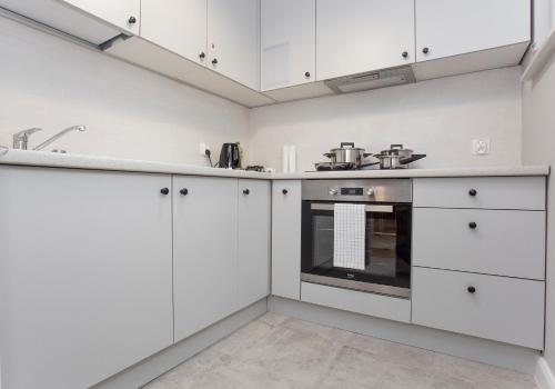 uma cozinha com armários brancos e um forno em CR Apartament Broniewskiego 15 em Bialystok
