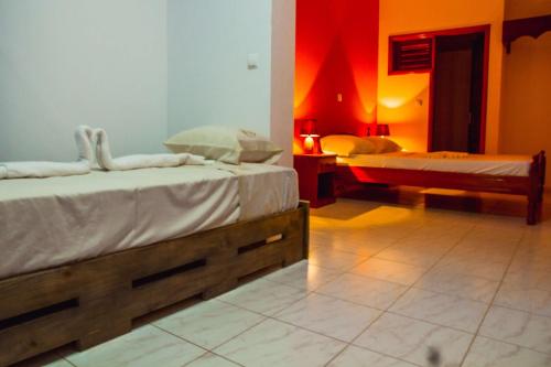 two beds in a room with red and orange walls at Pousada Green Place in Ribeira Grande