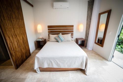 a bedroom with a large white bed and a mirror at Anjali Casa Divina in Sayulita