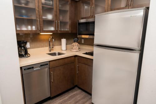 a kitchen with a white refrigerator and wooden cabinets at Staybridge Suites Coeur d'Alene by IHG in Coeur d'Alene