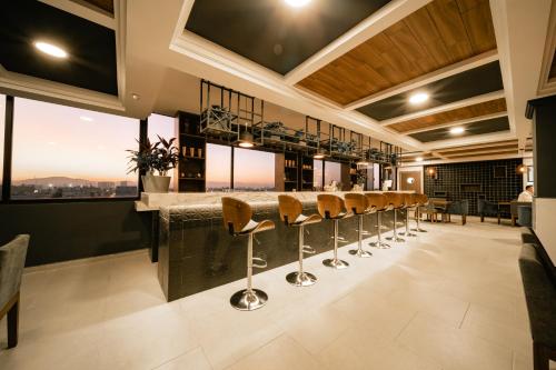 a bar with stools in a room with windows at Nuve in Torreón