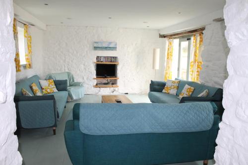 ペンブロークにあるThe Cottage @ Mill Haven placeのリビングルーム(青いソファ、テレビ付)
