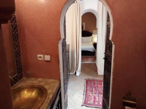 uma casa de banho com um lavatório dourado e um quarto em Riad Mina em Marraquexe
