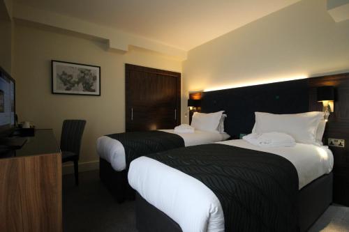 a hotel room with two beds and a desk at Holiday Inn London Kensington High St. by IHG in London