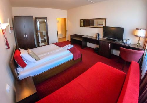 um quarto com uma cama, uma secretária e um sofá vermelho em Casa Veche em Sibiu