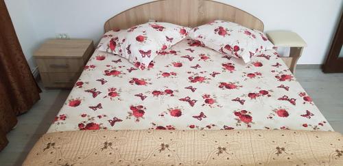 a bed with a bedspread with red flowers on it at Cazare Antonia in Curtea de Argeş