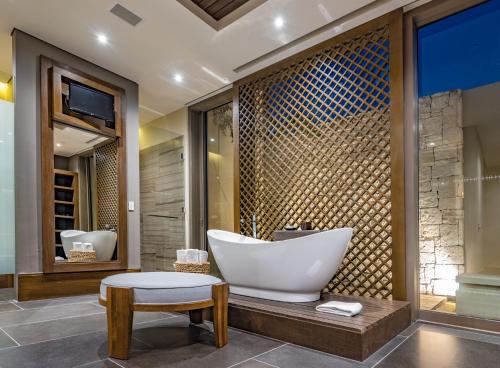 a bathroom with a tub and a sink and a stool at Nizuc Resort & Spa in Cancún
