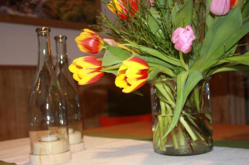 a vase of flowers sitting on a table with two bottles at Haus Berghoamat in Filzmoos