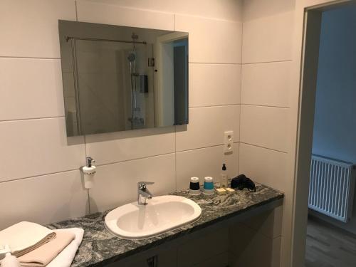 La salle de bains est pourvue d'un lavabo et d'un miroir. dans l'établissement Hotel-Restaurant Zum Onkel Jonathan, à Raeren