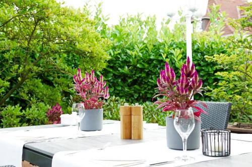 a table with two vases with pink flowers on it at Hünerbein's Posthotel in Schledehausen