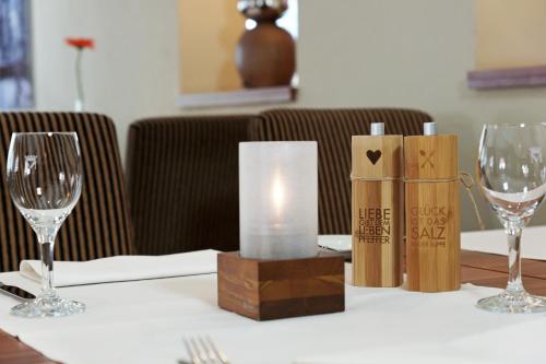 a table with a candle and two wine glasses on it at Hünerbein's Posthotel in Schledehausen