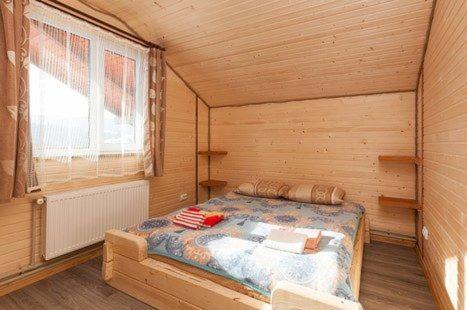 Un dormitorio con una cama en una cabaña de madera. en Шпінь 2, en Vorokhta