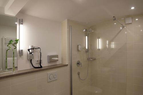 a shower with a glass door in a bathroom at Hünerbein's Posthotel in Schledehausen