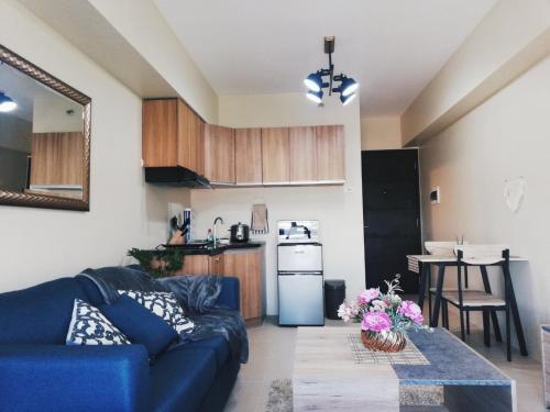 a living room with a blue couch and a kitchen at Cozy on the 28th! IT Park Cebu City in Cebu City