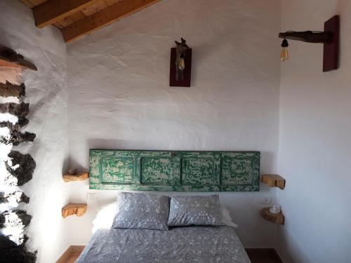 El Pinar del Hierro的住宿－Casa Rural Los Santillos，一间卧室配有一张带绿色床头板的床和时钟