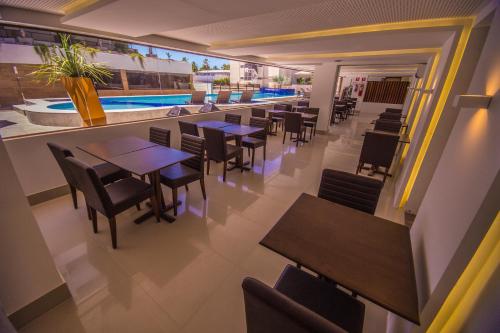 a restaurant with tables and chairs and a swimming pool at GOLDFLAT Cabo Branco by PenareiaTurBr in João Pessoa