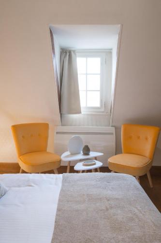 a bedroom with two chairs and a bed and a window at La Tonnellerie in Beaune