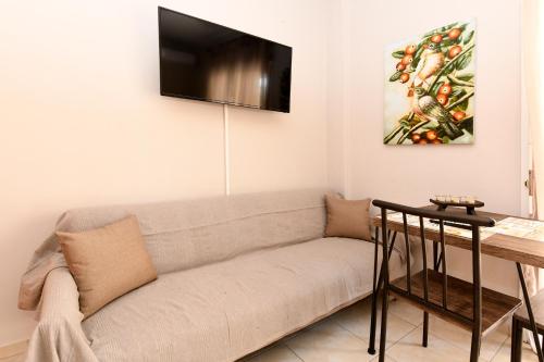 uma sala de estar com um sofá e uma televisão na parede em G&G Studio em Kavala