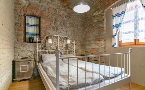 a bedroom with a metal bed in a stone wall at Koloska House in Balatonfüred