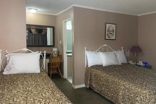 a hotel room with two beds with white pillows at Lucien Motel in Whitby