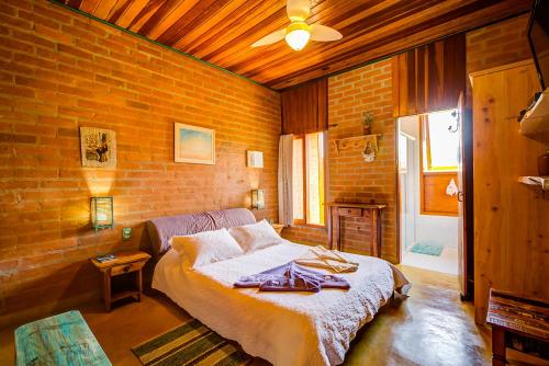 a bedroom with a bed and a brick wall at Hospedaria Estação Píccola No quintal da Pedra do Baú in São Bento do Sapucaí