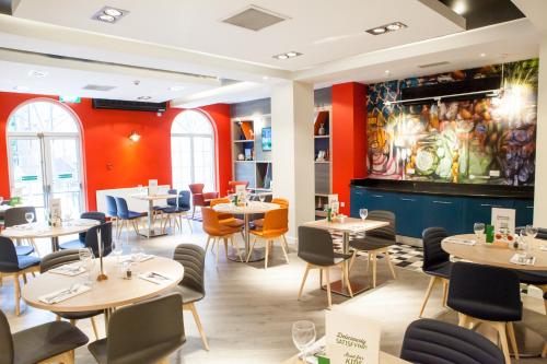 a restaurant with tables and chairs and a painting on the wall at Holiday Inn Corby Kettering Hotel & Spa in Corby
