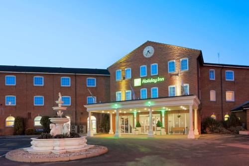 a hotel with a fountain in front of a building at Holiday Inn Corby Kettering Hotel & Spa in Corby