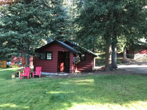 a red cabin with two pink chairs in the yard at Miette Hot Springs Bungalows in Jasper