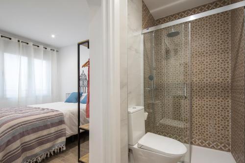 a bathroom with a shower and a toilet and a bed at Mirador del Zenete in Granada