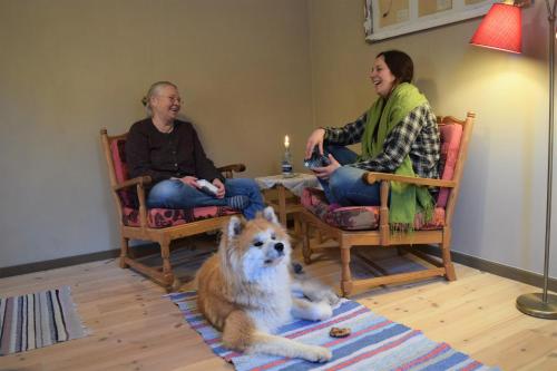 two women sitting in chairs with a dog laying on the floor at Ekologiska Fru Gran B&B i Tiveden in Gårdsjö