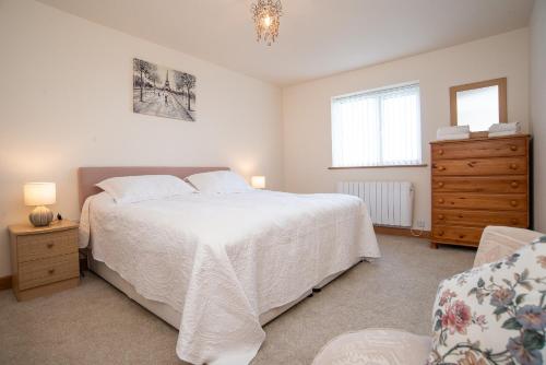 ein Schlafzimmer mit einem großen weißen Bett und einer Kommode in der Unterkunft Finest Retreats - Sea Views Cottage in Prestatyn