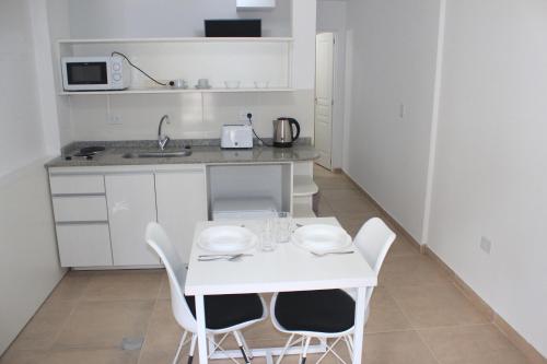 una pequeña cocina blanca con mesa blanca y sillas en NINA I en Ushuaia