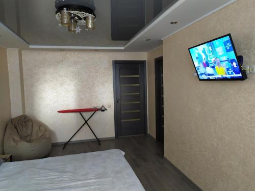 a room with a tv on the wall and a table at Апартаменты новострой улица Замостянская 34 А in Vinnytsya