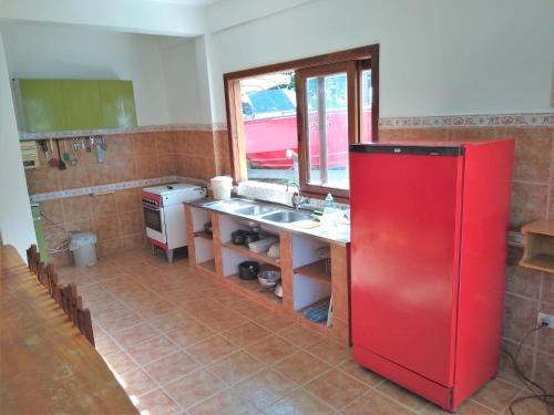 eine Küche mit einem roten Kühlschrank und einer Spüle in der Unterkunft Casa Beira-Mar 10pessoas 3 Suítes Térreo - A única realmente "Pé na Areia" c WiFi in Caraguatatuba