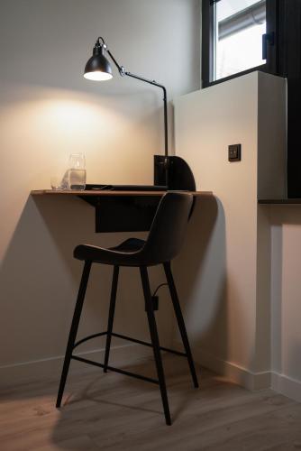 a desk with a chair and a lamp on it at THE ADAMS - Self Check In Hotel in Baden-Baden