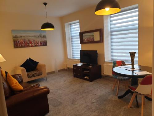 a living room with a tv and a table and chairs at The Old Inn at Plover Cottage Lindley in Huddersfield