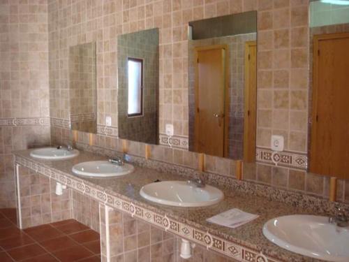a row of sinks in a bathroom with three mirrors at ALBERGUE TURÍSTICO DE CORNALVO in Trujillanos