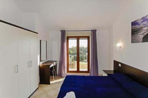 a bedroom with a blue bed and a desk and a window at I Girasoli in Bari Sardo