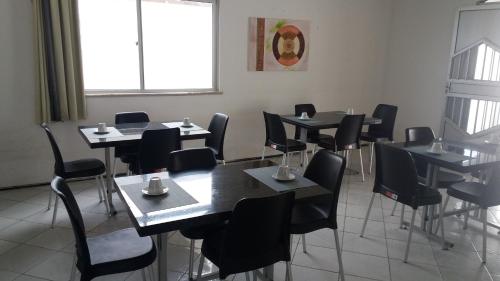a dining room with black tables and chairs and a window at Hotel Arco-Íris in Itapipoca