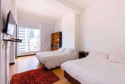 a bedroom with two beds and a tv and a window at Hotel Aparta Suite Continental Bogotá in Bogotá