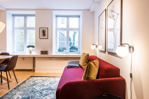 a living room with a red couch and two windows at Town Hall Apartments by Daniel&Jacob's in Copenhagen