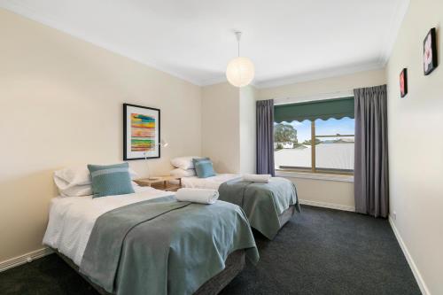 a hotel room with two beds and a window at SEA BREEZE on THE CRESCENT in Inverloch