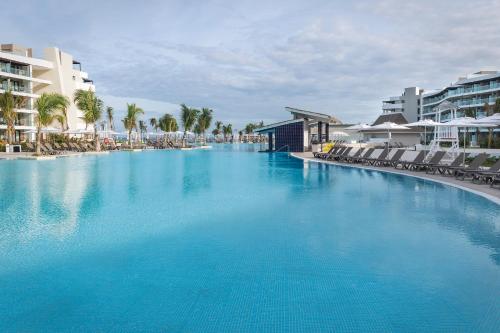 a large blue swimming pool with chairs and buildings at Ocean Coral Spring Resort - All Inclusive in Falmouth