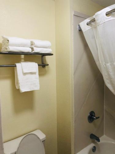 a bathroom with a shower and a toilet and towels at Days Inn & Suites by Wyndham Navarre - near Beaches Hurlburt in Navarre