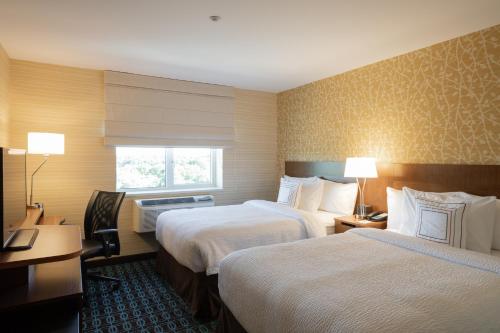 a hotel room with two beds and a desk at Fairfield Inn & Suites by Marriott New York Queens/Fresh Meadows in Queens