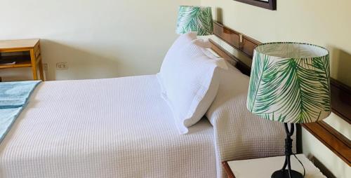 a bedroom with a white bed and a lamp at Hotel Acosta in Iquitos