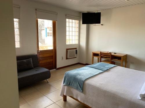 a bedroom with a bed and a chair and a desk at Hotel Acosta in Iquitos