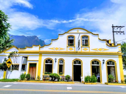 a yellow and white building with mountains in the background at Pousada e Restaurante Dona Siroba in Morretes